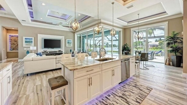 A spacious kitchen with a large island, pendant lighting, and a view of the outdoors. - Waterfront Luxury Retreat - Pool & Spa - Quick Harbor Access (Punta Gorda)