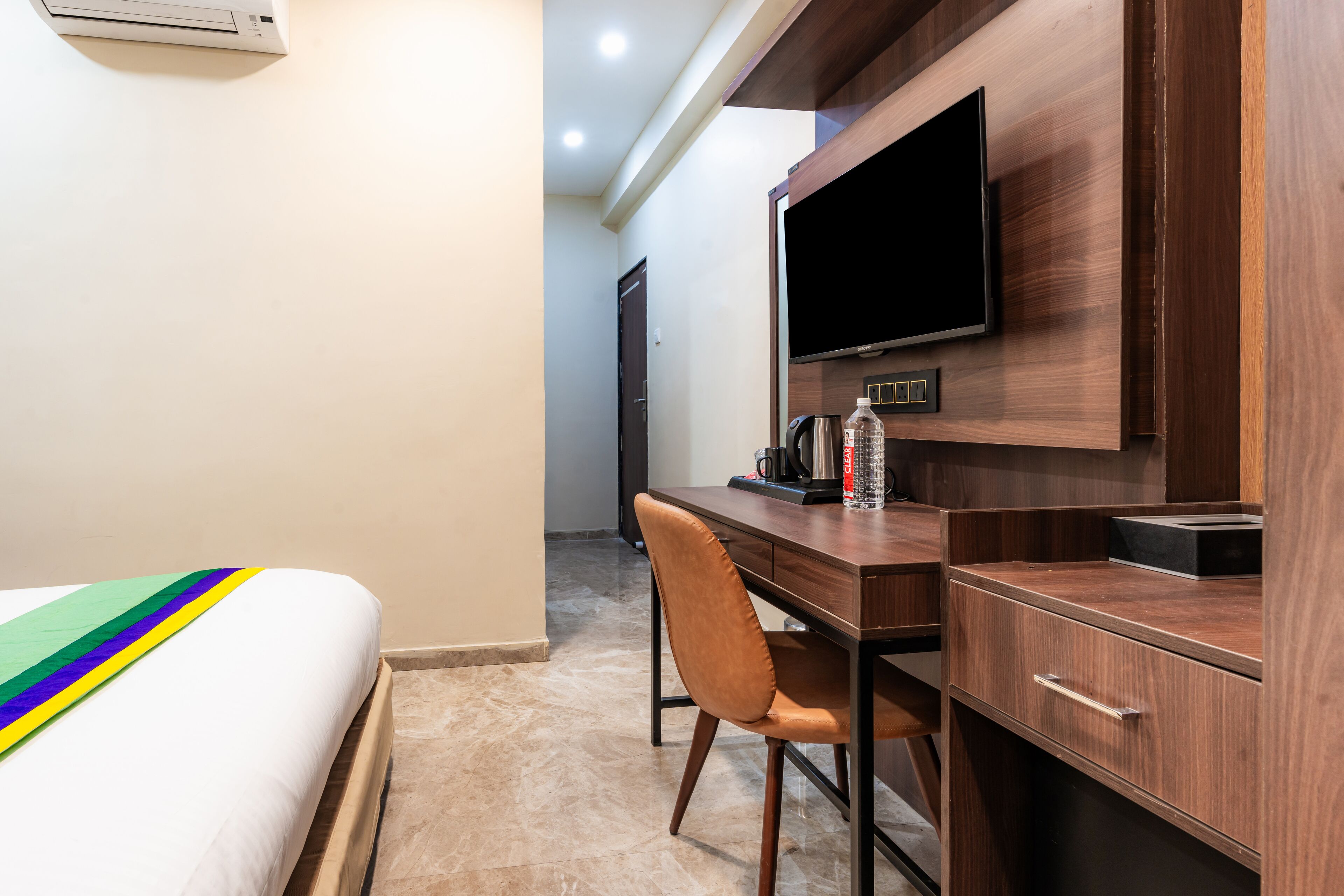 Ein Hotelzimmer mit Bett, Schreibtisch, Stuhl, Fernseher und Kaffeemaschine.