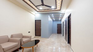 A hallway with a ceiling fan, a sofa, a coffee table, and a door at the end. - Treebo City Center (Nagpur)