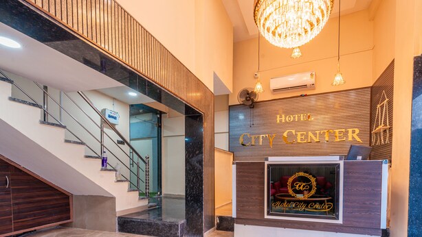 A hotel reception area with a modern design, featuring a grand chandelier, a reception desk, and a staircase leading to an upper level. - Treebo City Center (Nagpur)
