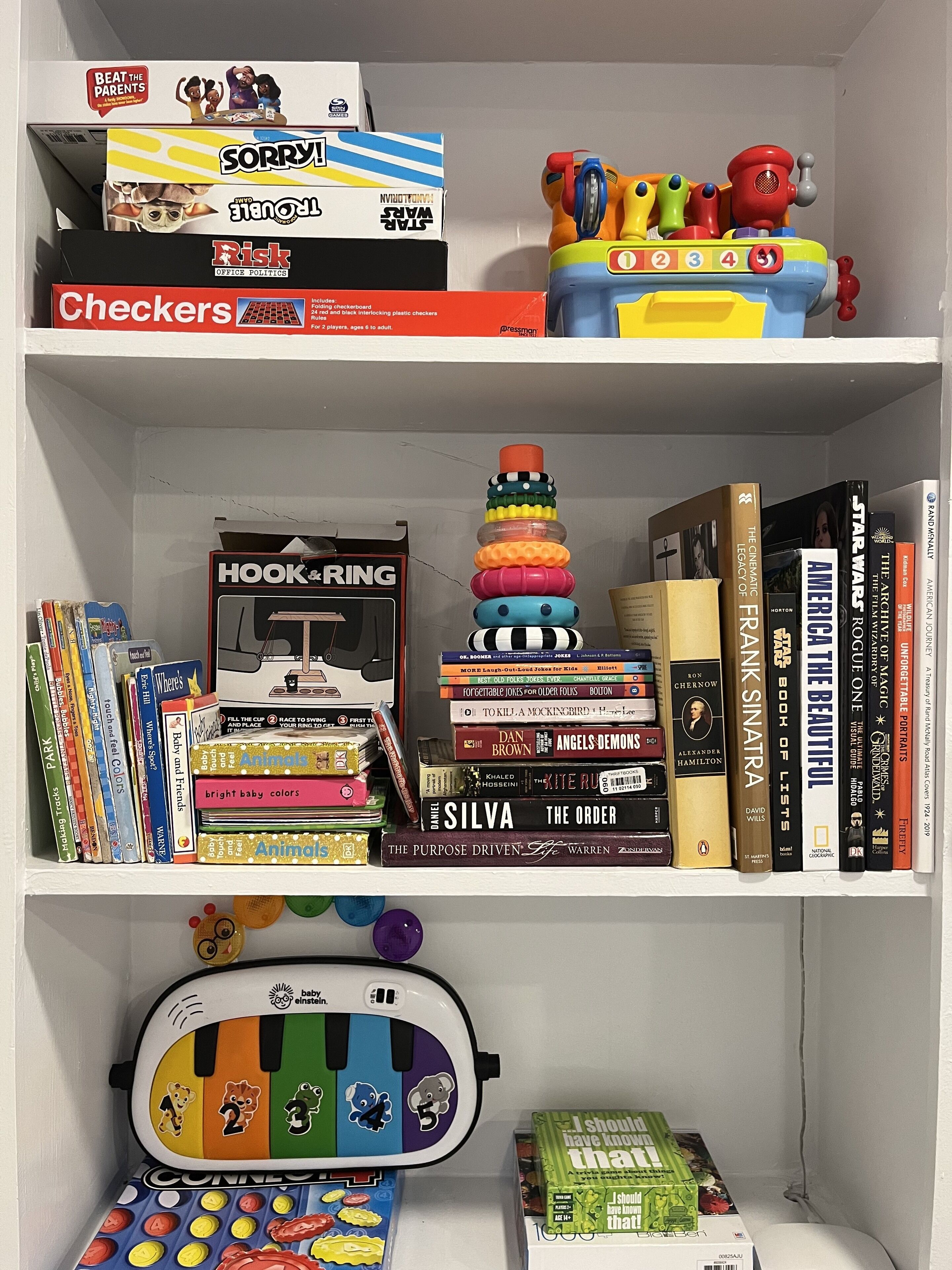 A bookshelf with various books, toys, and games.