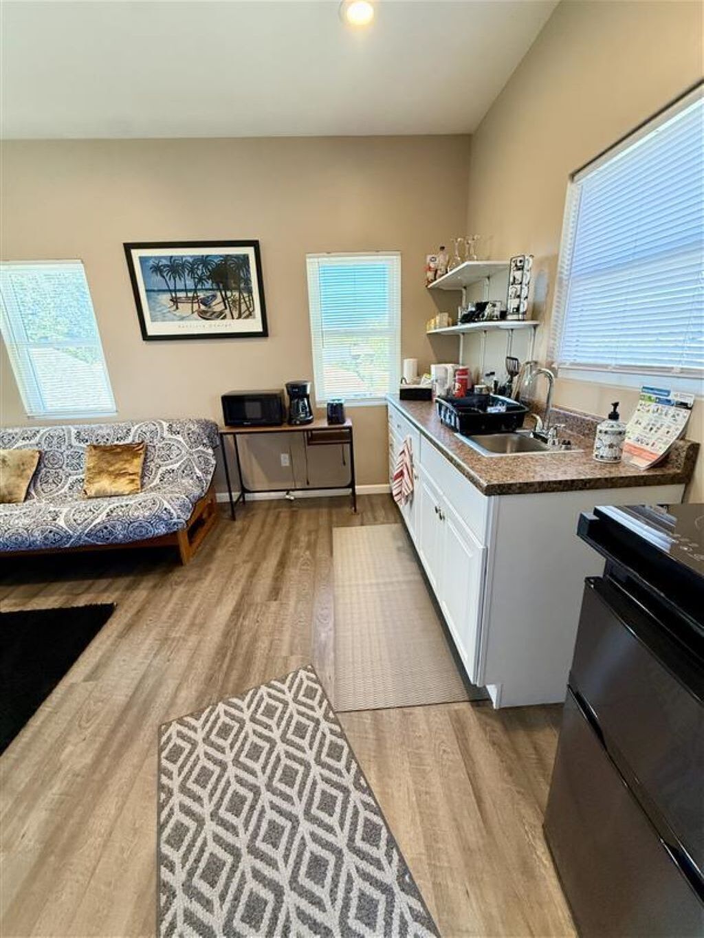 A compact living space with a kitchenette, a sofa, a coffee table, and a patterned rug.