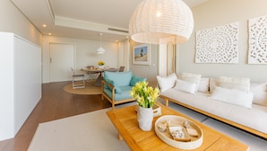 A modern living room with a wooden coffee table, a blue sofa, and a white couch. There is a dining area in the background with a table and chairs. - FLH Seaside Luxury at Madeira Palace Residence (Funchal)