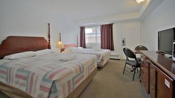 A hotel room with two beds, a desk, a television, and a chair.