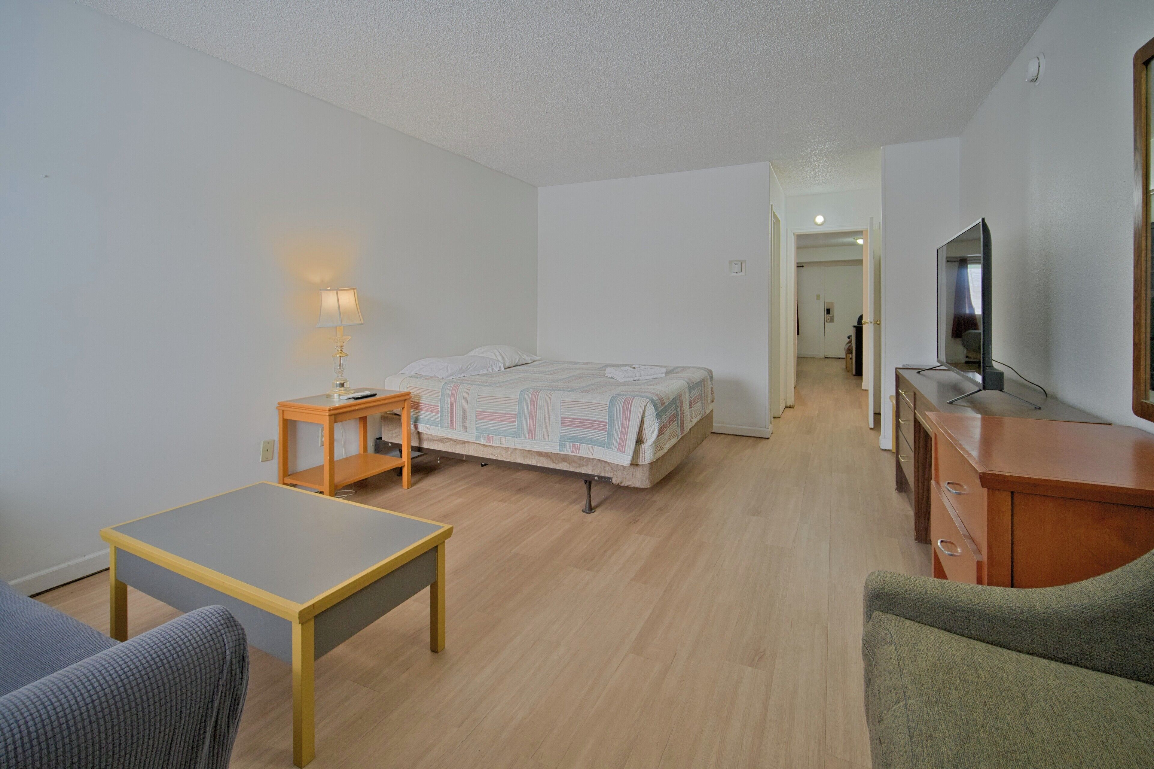 A small, clean room with a bed, a desk, a chair, and a TV.