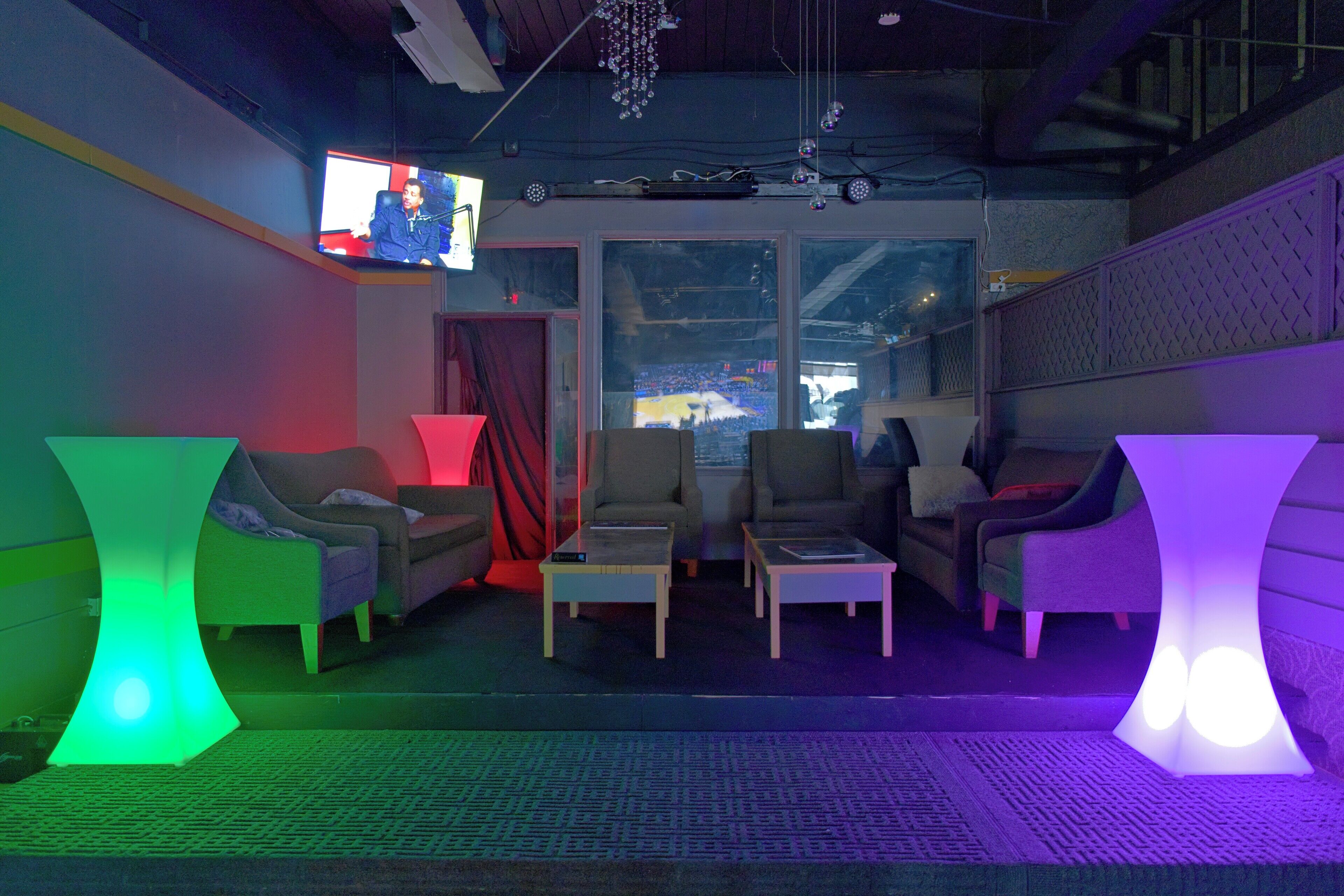 A room with a modern design, featuring a large window, a flat-screen TV, and a seating area with sofas and a coffee table.