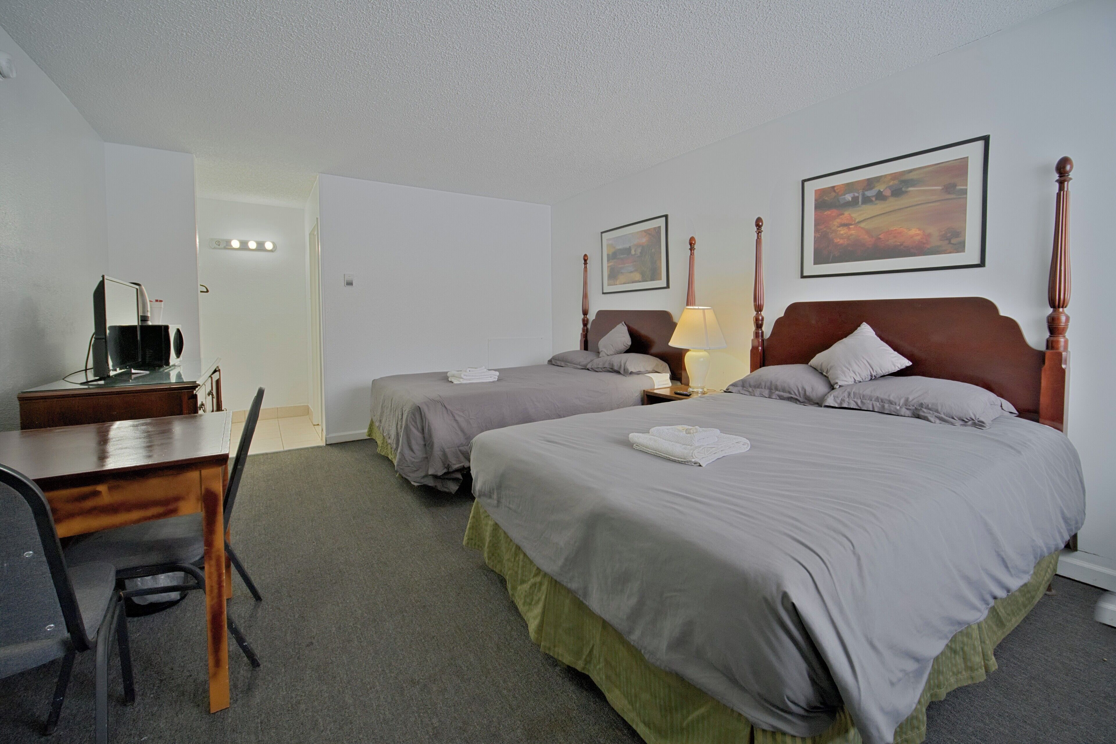 A hotel room with two beds, a desk, and a chair.