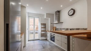 A modern kitchen with a stainless steel refrigerator, wooden countertop, and a built-in oven.
