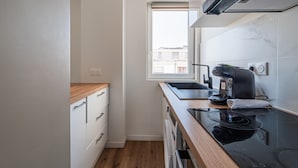 A compact kitchen with a window, a coffee machine, and a sink. - L'Escapade Strasbourgeoise - Magnifique petit T2 refait à neuf (Strasbourg)