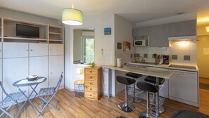 Een compacte keuken met een eethoek, inclusief een kleine tafel, stoelen, een barstoel en een magnetron.