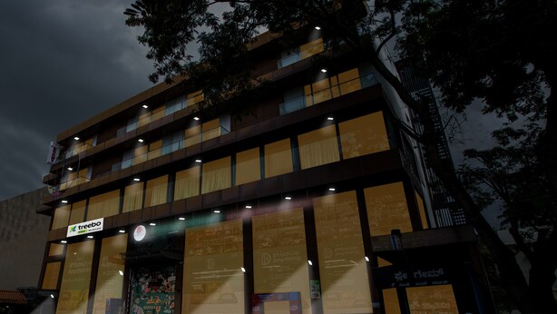 Un edificio de varios pisos con un diseño moderno, con grandes ventanales y un letrero que dice 'Treebo'.