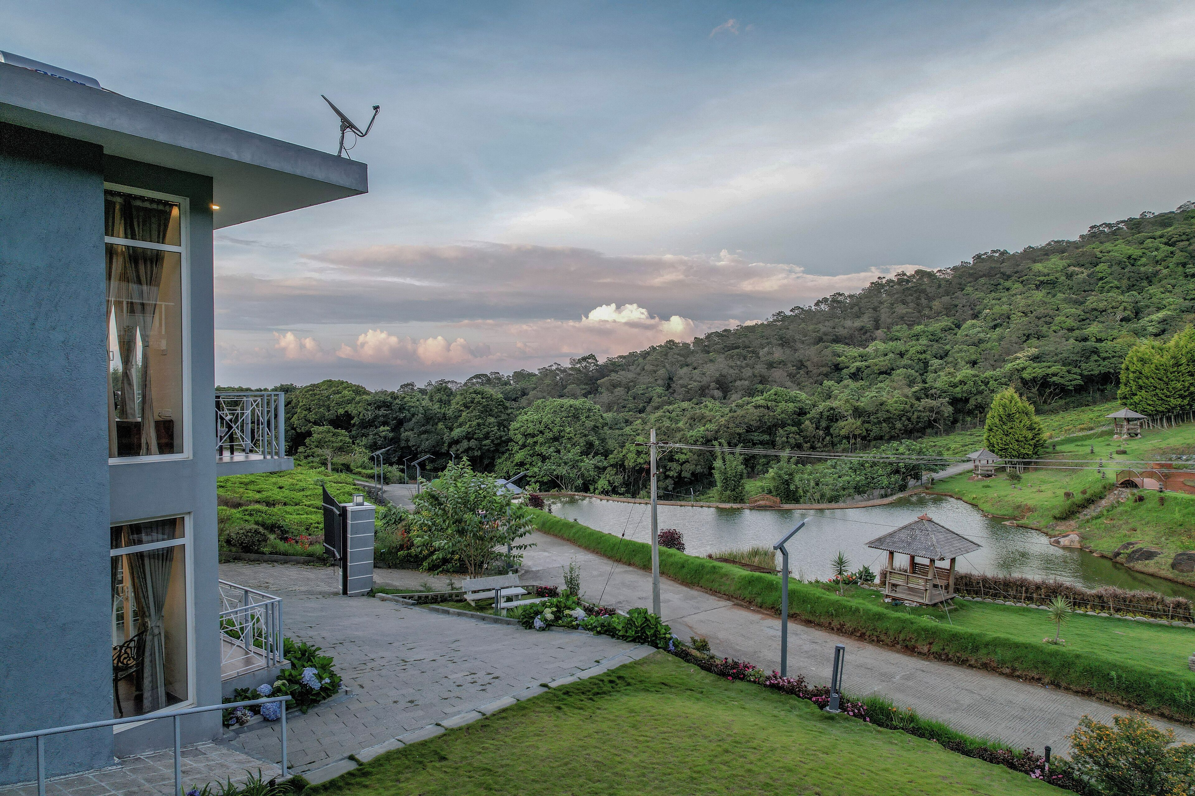 Un edificio moderno con un balcón que da a un jardín ajardinado y un lago.