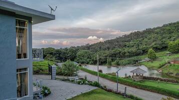 Un edificio moderno con un balcón que da a un jardín ajardinado y un lago.