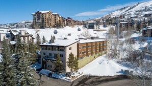 Une station de ski avec des bâtiments à plusieurs étages, un télésiège et un paysage enneigé.