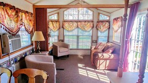 A cozy living room with a fireplace, comfortable seating, and large windows with curtains.