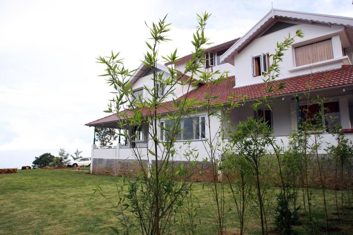 A two-story house with a red-tiled roof, a covered porch, and a grassy lawn.