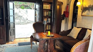 Une pièce chaleureuse avec un plafond en bois, une bibliothèque, une table à manger avec des chaises, un canapé et un tapis à motifs.