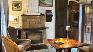 Une pièce chaleureuse avec une cheminée, une table en bois, un tapis à motifs et un fauteuil.