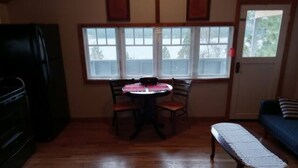 A room with a dining table, chairs, a bench, a refrigerator, and a window with a view of trees. - Best View of the Lake in Harrison (Harrison)