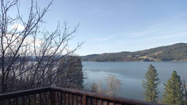 A wooden deck overlooking a lake with trees and hills in the background. - Best View of the Lake in Harrison (Harrison)