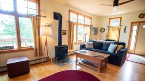 A cozy living room with a fireplace, a sofa, a coffee table, and a red rug. - Entire Home located in historical district (Bayfield)