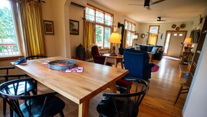 A dining area with a wooden table and black chairs, a blue sofa, and a television in the background. - Entire Home located in historical district (Bayfield)