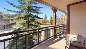 A balcony with a view of a large evergreen tree and a road. - The Corral at Breckenridge #206S By Summit County Mountain Retreats (Breckenridge)