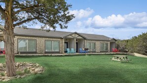 Una casa de piedra con un amplio jardín, mobiliario exterior y una zona de barbacoa.