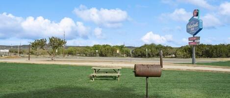 A grassy area with two green chairs, a picnic table, and a mailbox. A sign for MotorBeat Inn is visible in the background.