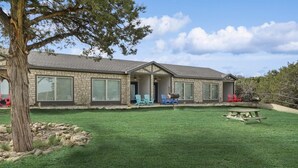 A two-story house with a covered patio, a lawn, and outdoor seating. - MotorBoat Inn Suite 10 (Graford)
