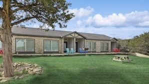 A stone house with a covered patio, a lawn, and a picnic table. - MotorBoat Inn Suite 15 (Graford)