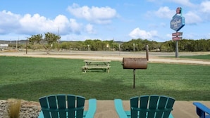 A grassy area with two green chairs, a picnic table, and a mailbox. A sign for MotorBeat Inn is visible in the background. - MotorBoat Inn Suite 15 (Graford)