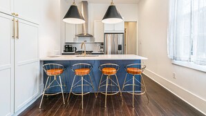 A modern kitchen with a central island, stainless steel appliances, and bar stools. - Irish Channel Stunner! (New Orleans)