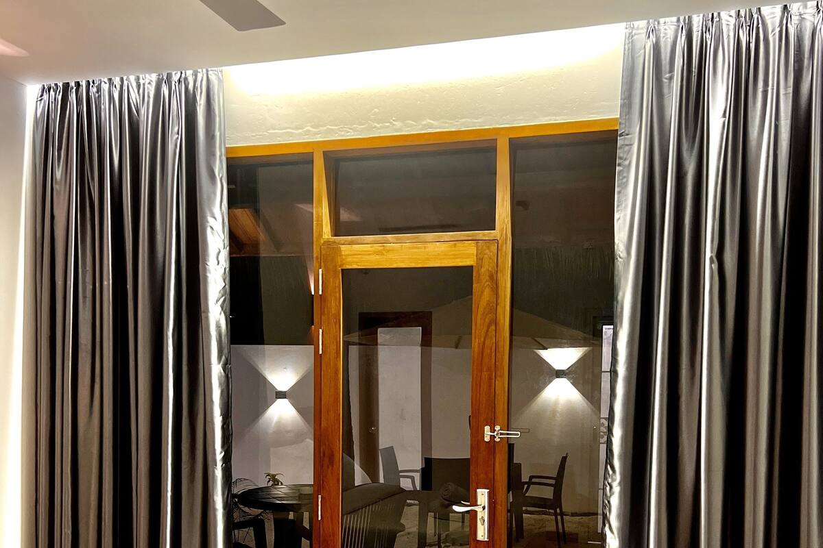 A hotel room with a bed, a sliding glass door to a balcony, and curtains.