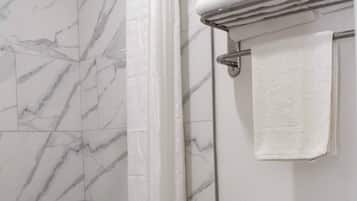 Un baño con ducha, inodoro y piso de baldosas.
