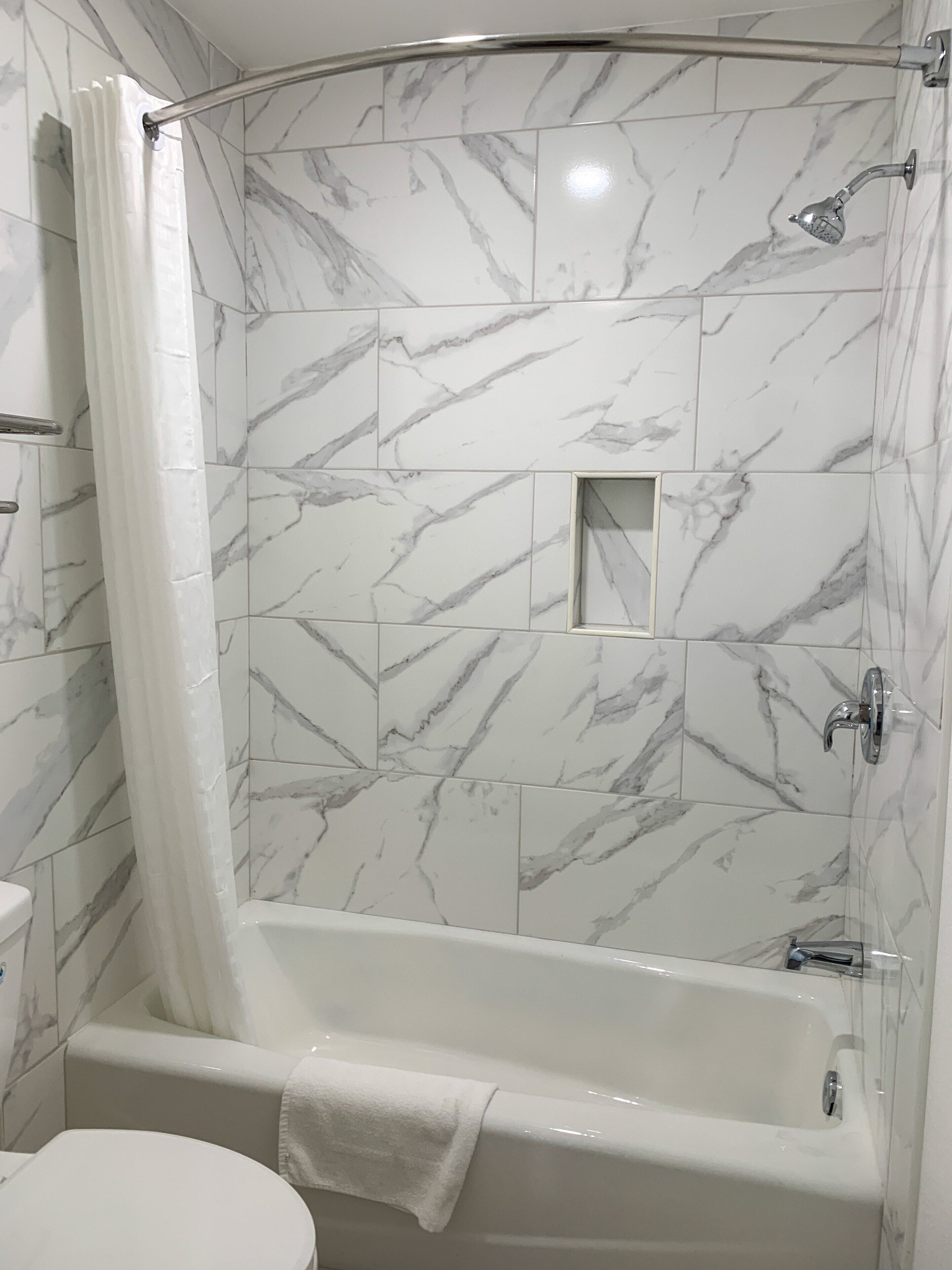 Une salle de bain avec douche, toilettes et baignoire.