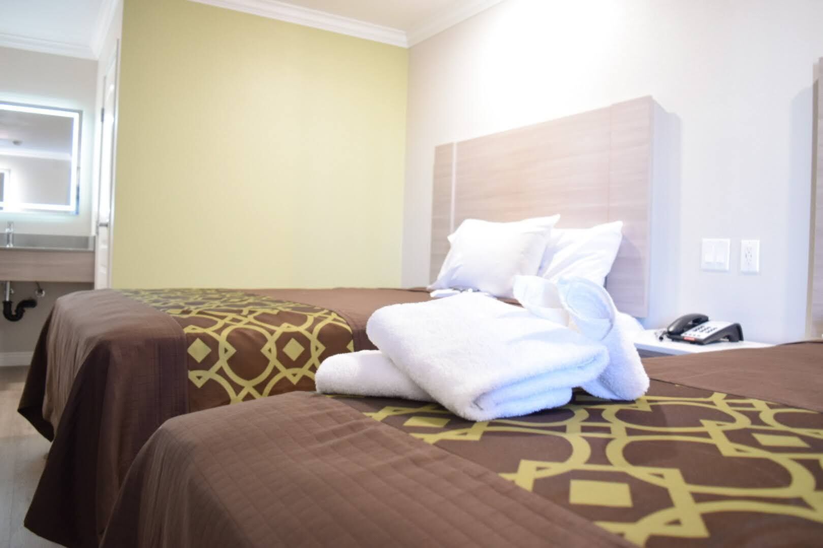 Une chambre d’hôtel avec deux lits, chacun agrémenté d’une couvre-lit à motifs, d’une tête de lit et d’un téléphone posé sur une table de chevet.