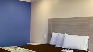 A hotel room with a large bed, a nightstand, and a blue accent wall.