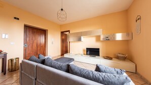 A modern living room with a grey sofa, a TV, and a white cabinet. - #914 Home in Irpinia (Nusco)