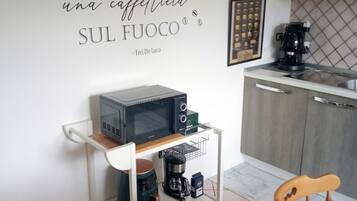 Eine Küchenzeile mit einer Kaffeemaschine, einer Mikrowelle und einer Kaffeemühle auf einem Wagen.