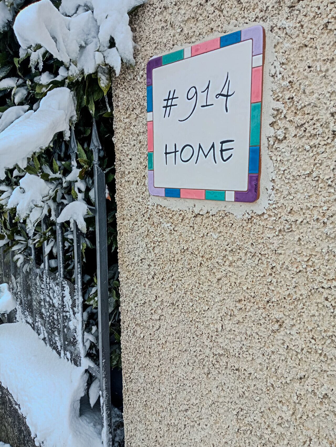 Un cartel de número de casa con la inscripción '#914 HOME' sobre una pared con textura.