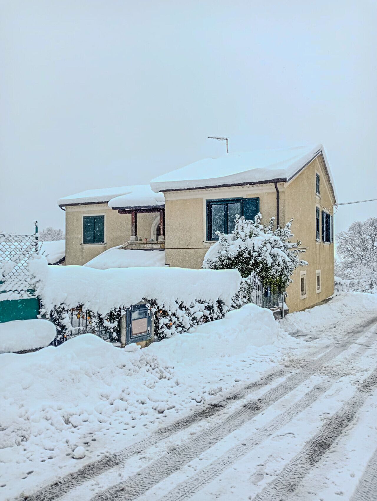 Ein zweistöckiges Haus mit verschneitem Dach und Auffahrt.