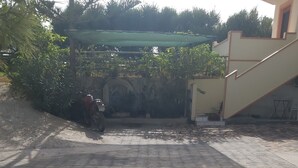 Une cour dallée où est garée une moto, sur le côté gauche.