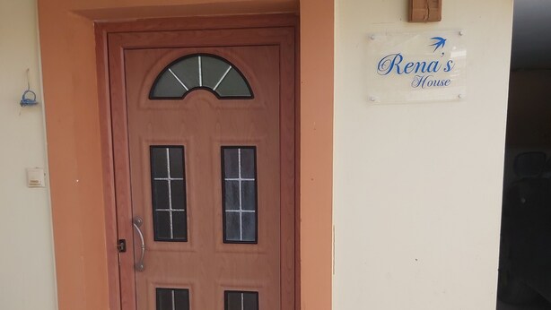 Une porte en bois sur laquelle est accrochée une enseigne indiquant « Chez Rena ».