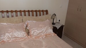 Un lit bien fait, avec une couvre-lit rose, deux oreillers et deux serviettes.