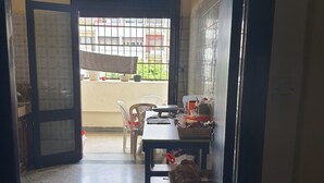 Une pièce avec une fenêtre, une table, des chaises et une porte.