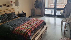 Une chambre à coucher avec un lit, une table de chevet, une lampe, une chaise et une vue par la fenêtre.