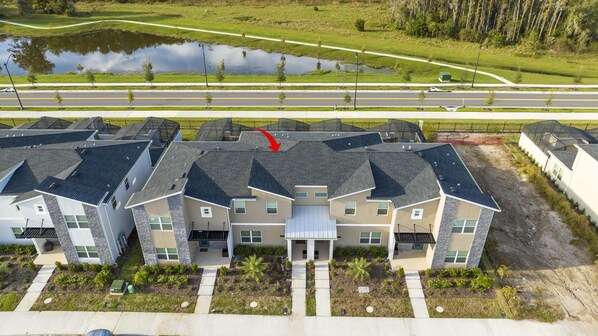 A modern residential complex with multiple two-story houses, a central driveway, and a nearby road.