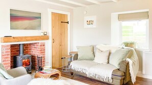 A cozy living room with a fireplace, a sofa, a chair, and a coffee table. - South Riccalton Farm Cottage (Jedburgh)