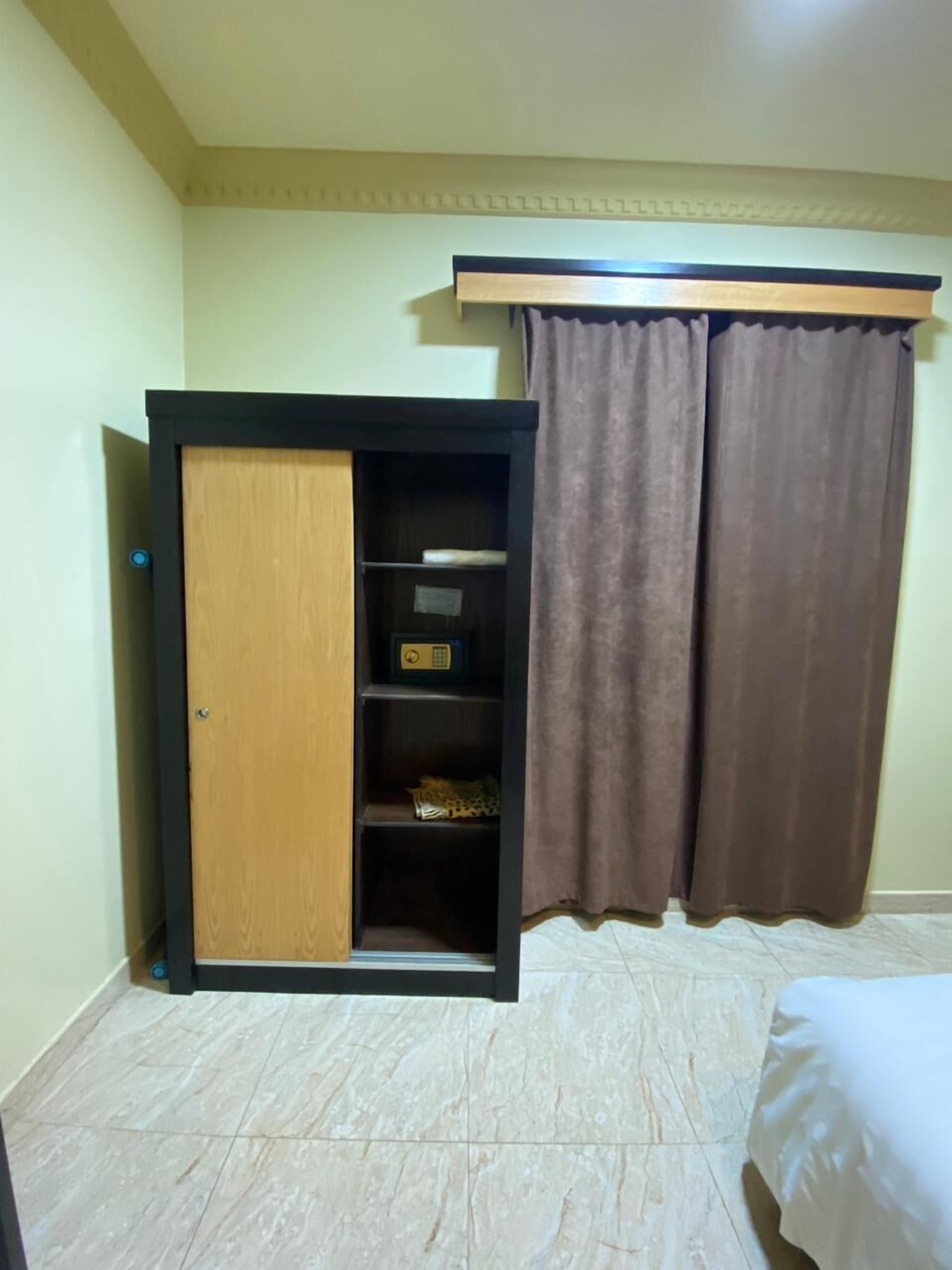 Una habitación con armario, cama y cortina.
